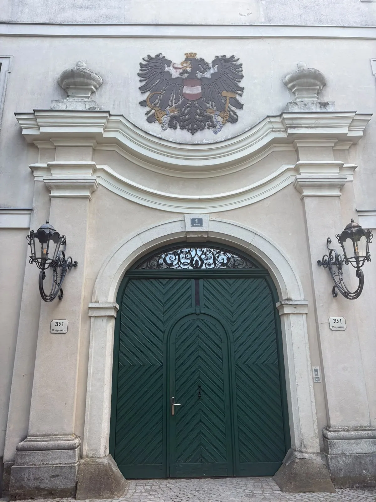 Das grüne Eingangstor von Schloss Wolfpassing mit dem österreichischen Wappen